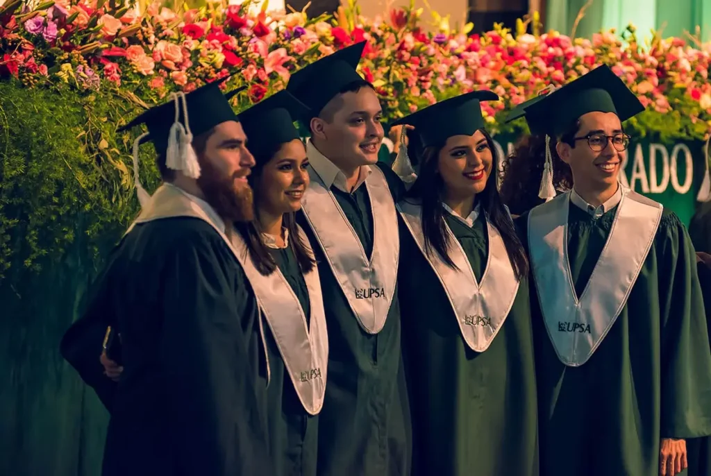 Foto de un grupo de amigos abrazados celebrando su graduación al aire libre.