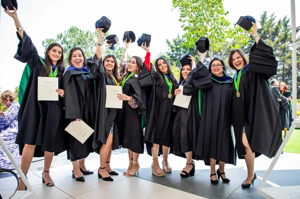 Foto de un grupo de graduados sonriendo con birretes y toga.